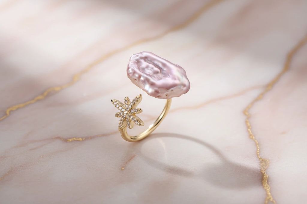 Perlenring mit Sternenstaub-Akzent von flyliving, auf einem marmorierten Untergrund mit goldenen Adern liegend.