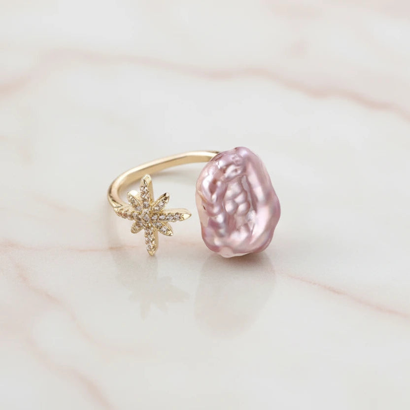 Goldener Sternenstaub-Perlenring von flyliving mit einem großen, rosa Barockperlen-Akzent.