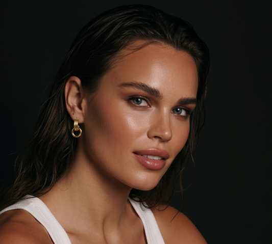 Gold-plated stainless steel geometric loop drop earrings by flyliving, worn by a model in a white tank top.
