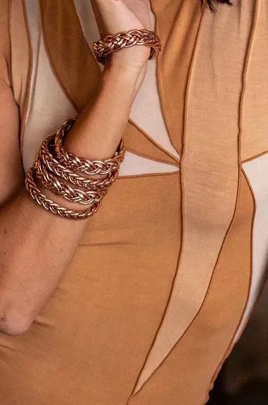 Goldene und silberne Armreifen am Handgelenk einer Person auf hellem Holzfußboden – eleganter Schmuck für Damen, modernes Armband-Design