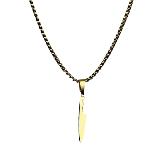 Die goldene Halskette „Laura“ von flyliving präsentiert einen Kochmesser-Anhänger als eleganten Edelstahl-Anhänger, der sich vor einem schlichten schwarzen Hintergrund abhebt.