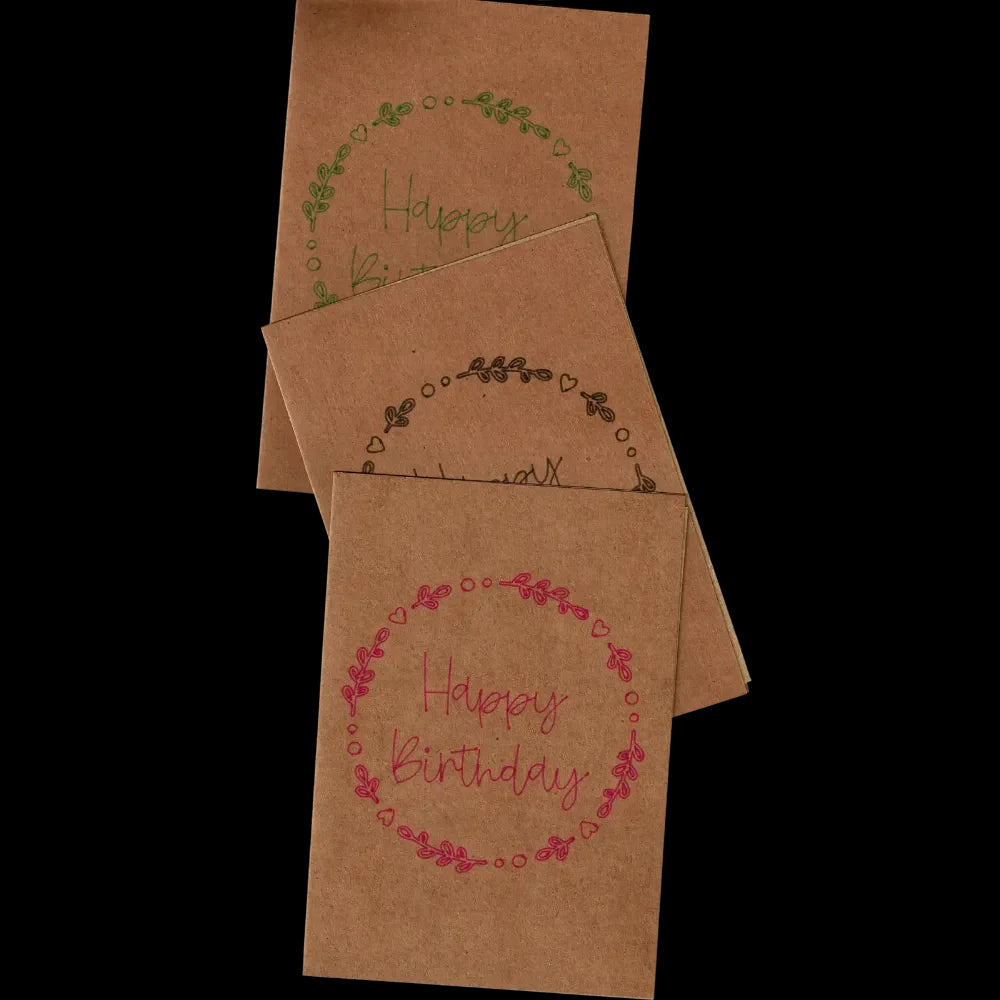 "Geburtstagskarten aus braunem Kraftpapier mit verschiedenfarbigen Schriftzug „Happy Birthday“ und floraler Verzierung aus Blättern und Herzen. Nachhaltiges Design, ideal für umweltbewusste Glückwünsche. Perfekt für persönliche und stilvolle Geburtstagsgrüße."