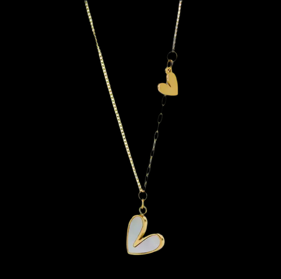 "Die goldene Halskette „Uschi“ von flyliving präsentiert zwei Edelstahl-Herzan-Anhänger, ein größeres mit Muscheleinlage und ein kleineres, an einer filigranen Kette – stilvoll inszeniert vor schwarzem Hintergrund."