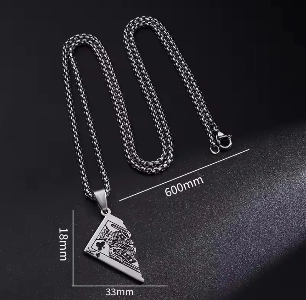 "Die Halskette „Erna“ von flyliving in Silber ist eine Halskette aus Edelstahl in Silber mit einer 600 mm langen Kette und einem dreieckigen (33 x 18 mm) Anhänger mit eingravierten Löwen- und Kartenmotiven, inspiriert von Halbspielkarten-Designs, auf Schwarz mit Maßangaben dargestellt."