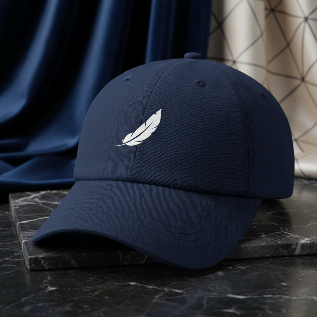 Navy blue baseball cap by flyliving with an embroidered white feather logo, shown in a front-side view on dark marble.