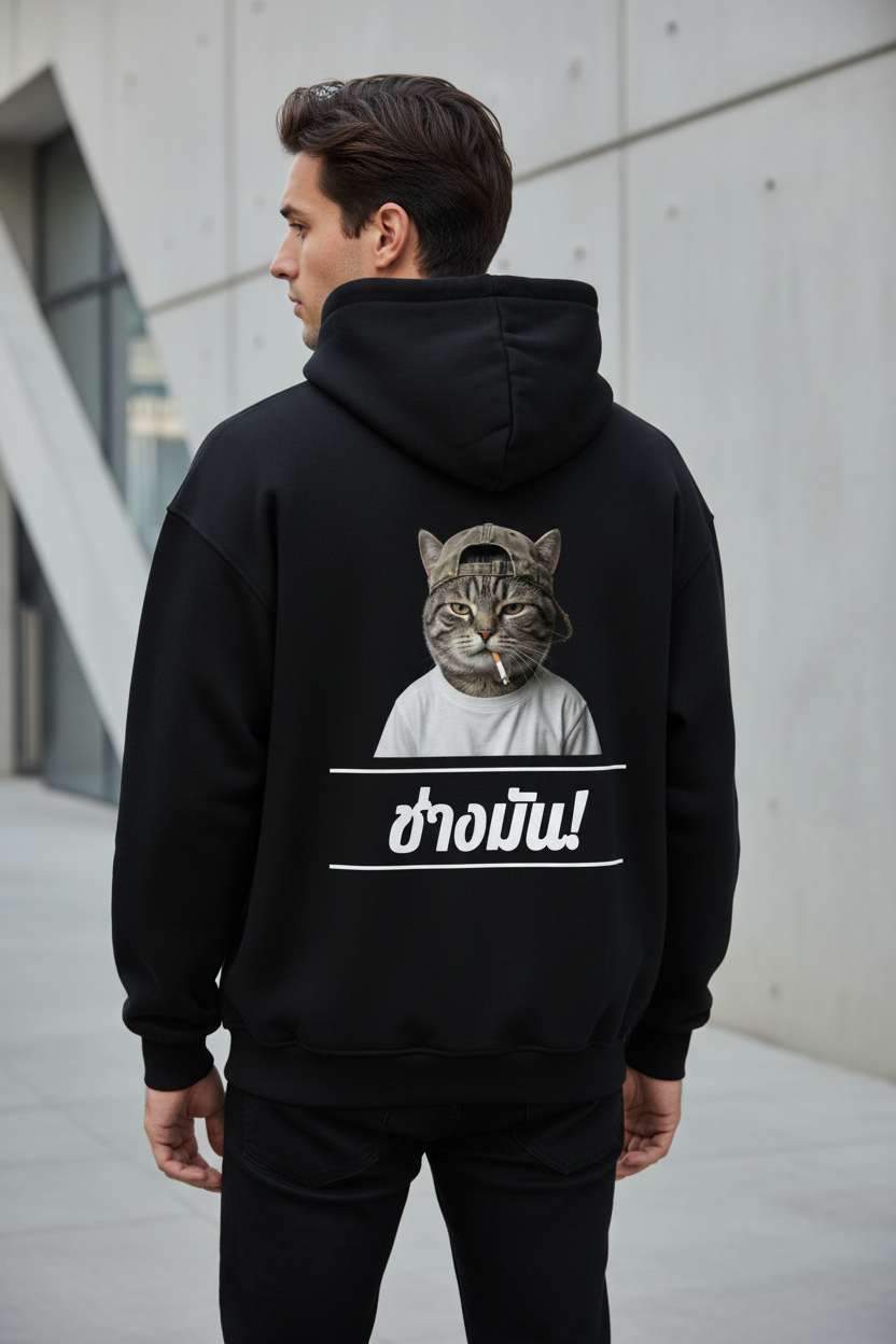 Black oversized hoodie by flyliving featuring a graphic of a cat in a hat smoking and Thai text 'ช่างมัน!' on the back, worn by a man.