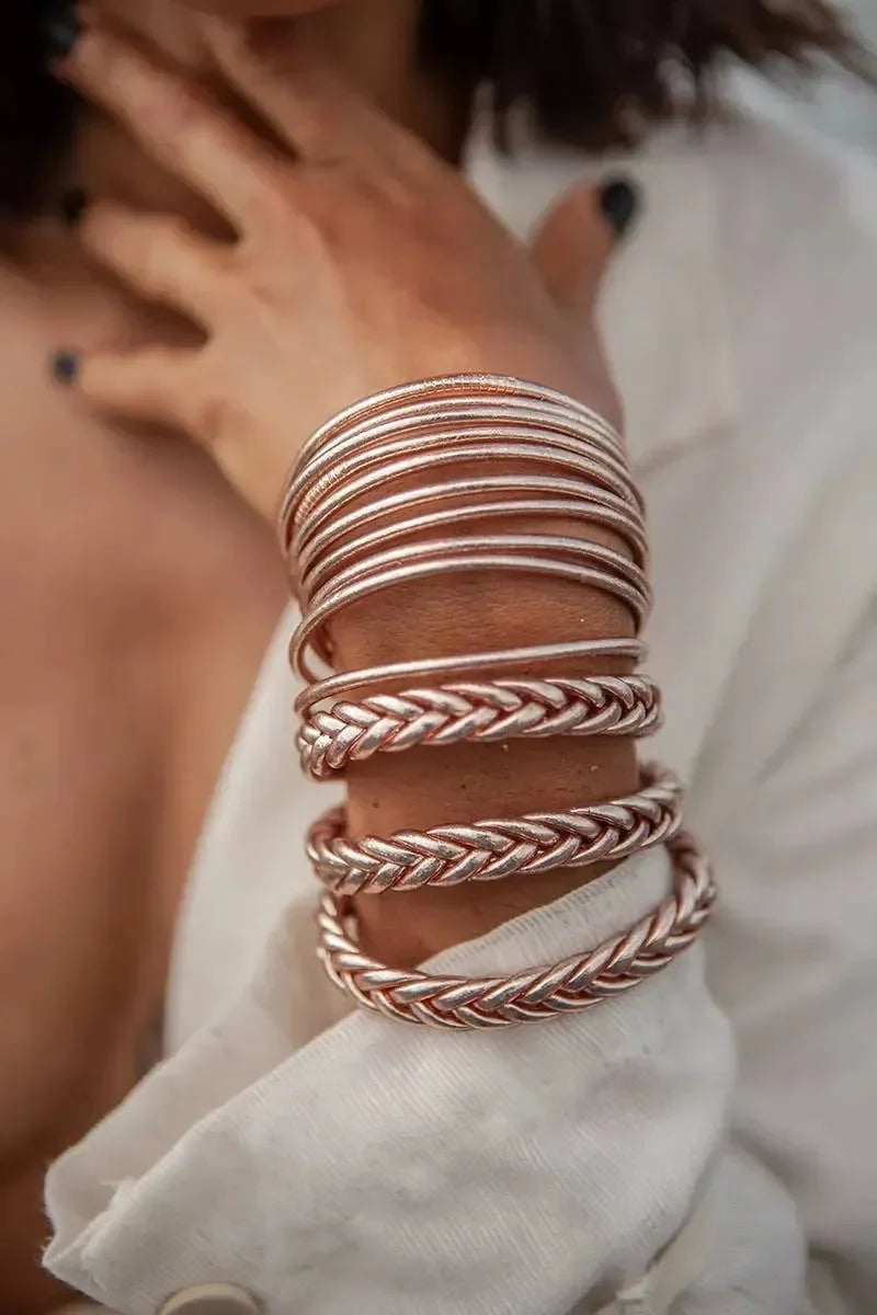 Goldene und silberne Armreifen am Handgelenk einer Person auf hellem Holzfußboden – eleganter Schmuck für Damen, modernes Armband-Design