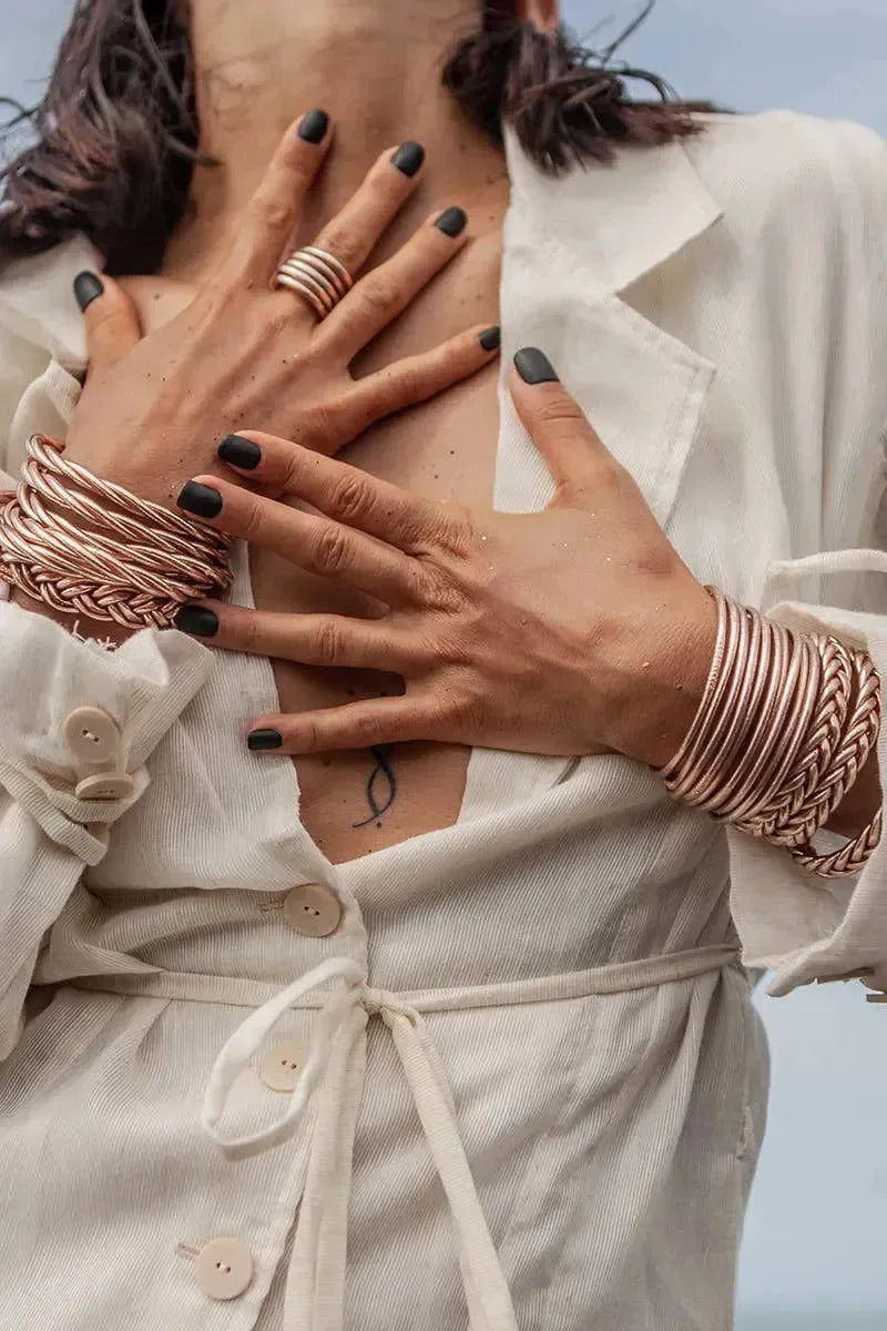 Goldene und silberne Armreifen am Handgelenk einer Person auf hellem Holzfußboden – eleganter Schmuck für Damen, modernes Armband-Design