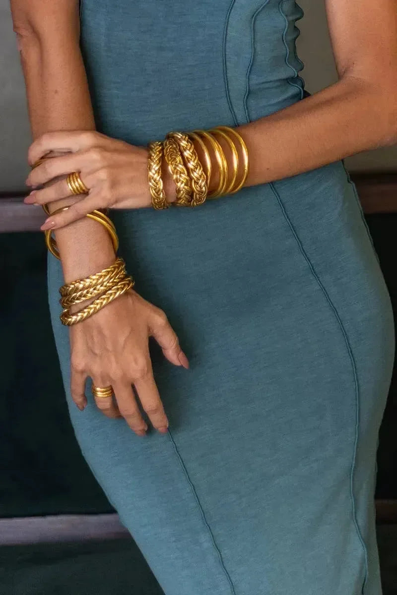 Goldene und silberne Armreifen am Handgelenk einer Person auf hellem Holzfußboden – eleganter Schmuck für Damen, modernes Armband-Design