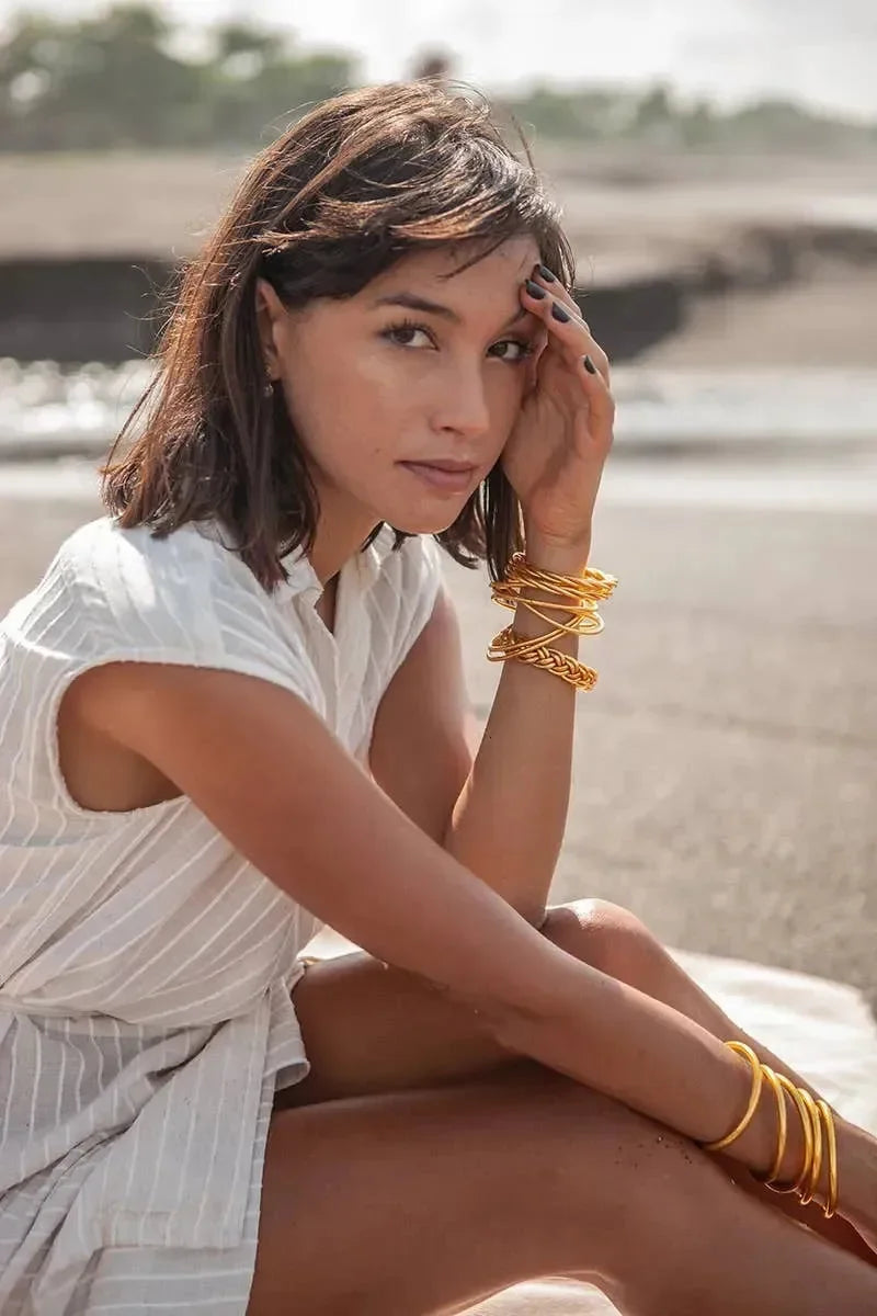 Goldene und silberne Armreifen am Handgelenk einer Person auf hellem Holzfußboden – eleganter Schmuck für Damen, modernes Armband-Design