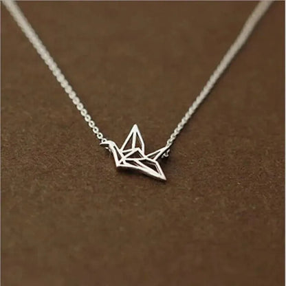 Die Halskette „Wilhelm“ von flyliving ist eine filigrane Silberkette mit Kranich-Anhänger aus 925 Sterling Silber, präsentiert auf braunem Hintergrund.