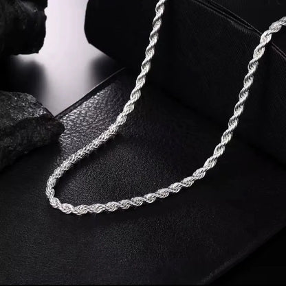 Die Halskette „Helga“ aus Silber von flyliving mit filigran gedrehtem Design liegt auf schwarzem Leder, während dunkle Steine im Hintergrund die elegante Gliederkette stilvoll in Szene setzen.