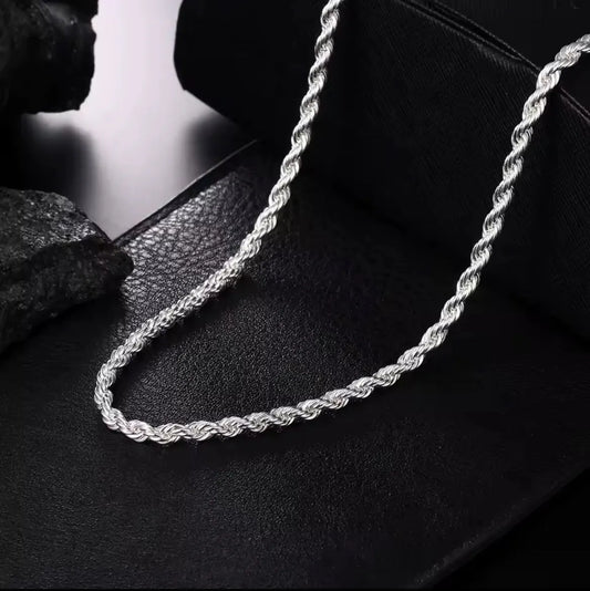 Die Halskette „Helga“ aus Silber von flyliving mit filigran gedrehtem Design liegt auf schwarzem Leder, während dunkle Steine im Hintergrund die elegante Gliederkette stilvoll in Szene setzen.