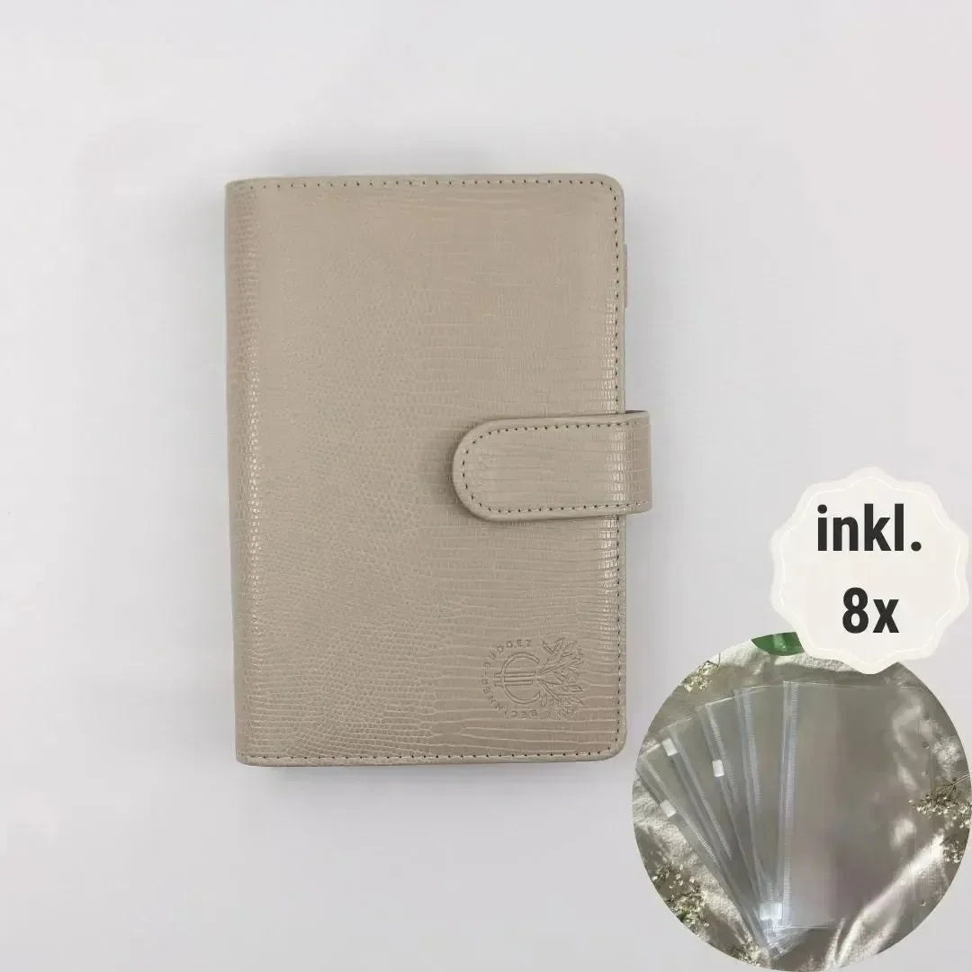 Der Budget Binder "Gecko" - Personal (A6) von BeginnerBudget ist in grauem strukturiertem Leder mit Druckknopfverschluss abgebildet. Ein Einschub hebt 8 mitgelieferte transparente Kartenhüllen hervor, die mit "inkl." beschriftet sind. 8x", für Sparziele oder Finanzübersicht.
