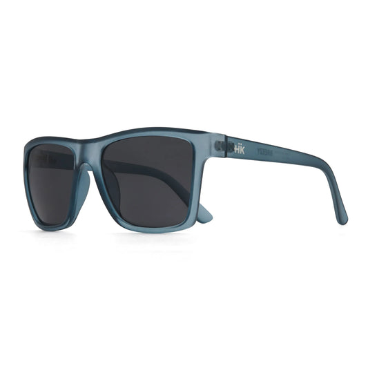 Die Sonnenbrille Breezy Blue Hanukeii von INDICOM BRANDS SL hat einen blauen, rechteckigen Rahmen, Gläser aus Polycarbonat mit UV400-Schutz und zeigt das Markenlogo auf dem Bügel, das schräg auf weißem Hintergrund abgebildet ist.