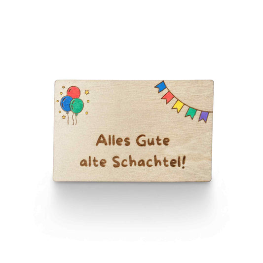 Wooden gift card by flyliving, engraved with "Alles Gute alte Schachtel!" alongside colorful balloons and party bunting.