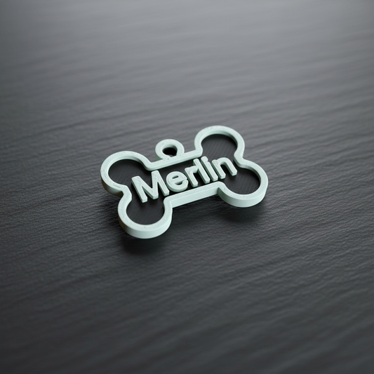Personalisierter weißer hundeanhänger aus nachhaltigem PLA mit dem namen merlin in moderner schrift graviert