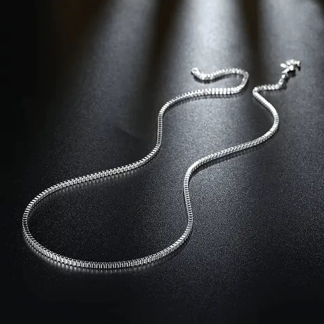 Die Halskette „Inga“ aus Silber von flyliving liegt elegant auf dunklem, strukturiertem Untergrund, das Licht reflektiert vom Silber und verleiht ihr einen edlen, glänzenden Look.