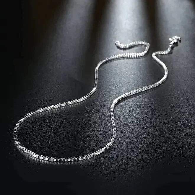 Die Halskette „Inga“ aus Silber von flyliving liegt elegant auf dunklem, strukturiertem Untergrund, das Licht reflektiert vom Silber und verleiht ihr einen edlen, glänzenden Look.