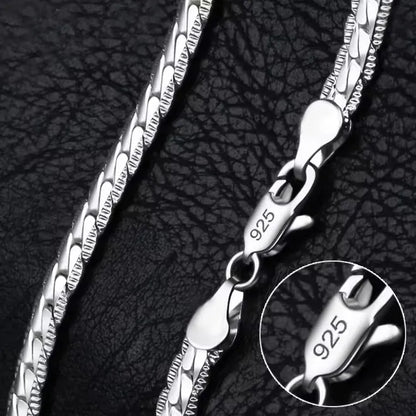 Eine Nahaufnahme der flyliving Halskette „Horst-Peter“, einer silbernen Gliederkette mit einem 925er Sterlingsilber-Karabinerverschluss, dargestellt auf strukturiertem Schwarz. Ein Einschub hebt die 925er-Markierung auf dem Verschluss hervor.