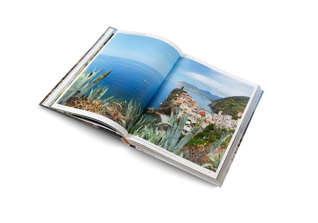 Ein aufgeschlagenes Buch von gestalten EU Shop's Wanderlust Mittelmeer zeigt ein atemberaubendes Foto einer mediterranen Stadt - blaues Meer, grüne Hügel und Agaven - perfekt für Fans von mediterranen Wanderwegen und Tourentipps.