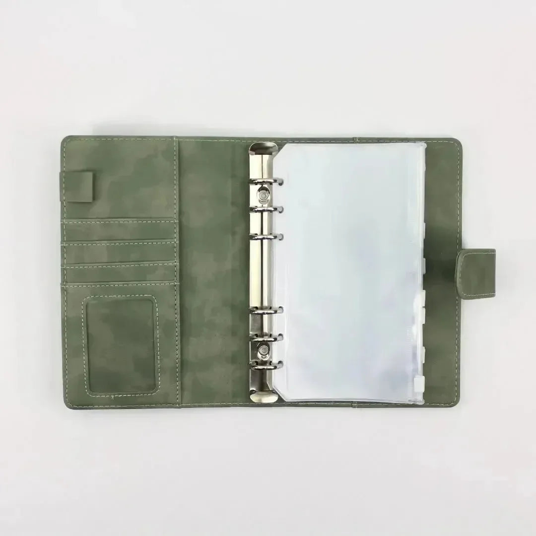 Der BeginnerBudget Budget Binder (veganes) Wildleder - Personal (A6) in grün verfügt über Kartenfächer auf der linken Seite und eine Sechsringmechanik aus Metall mit Klarsichthüllen auf der rechten Seite, abgebildet auf einer schlichten weißen Oberfläche.