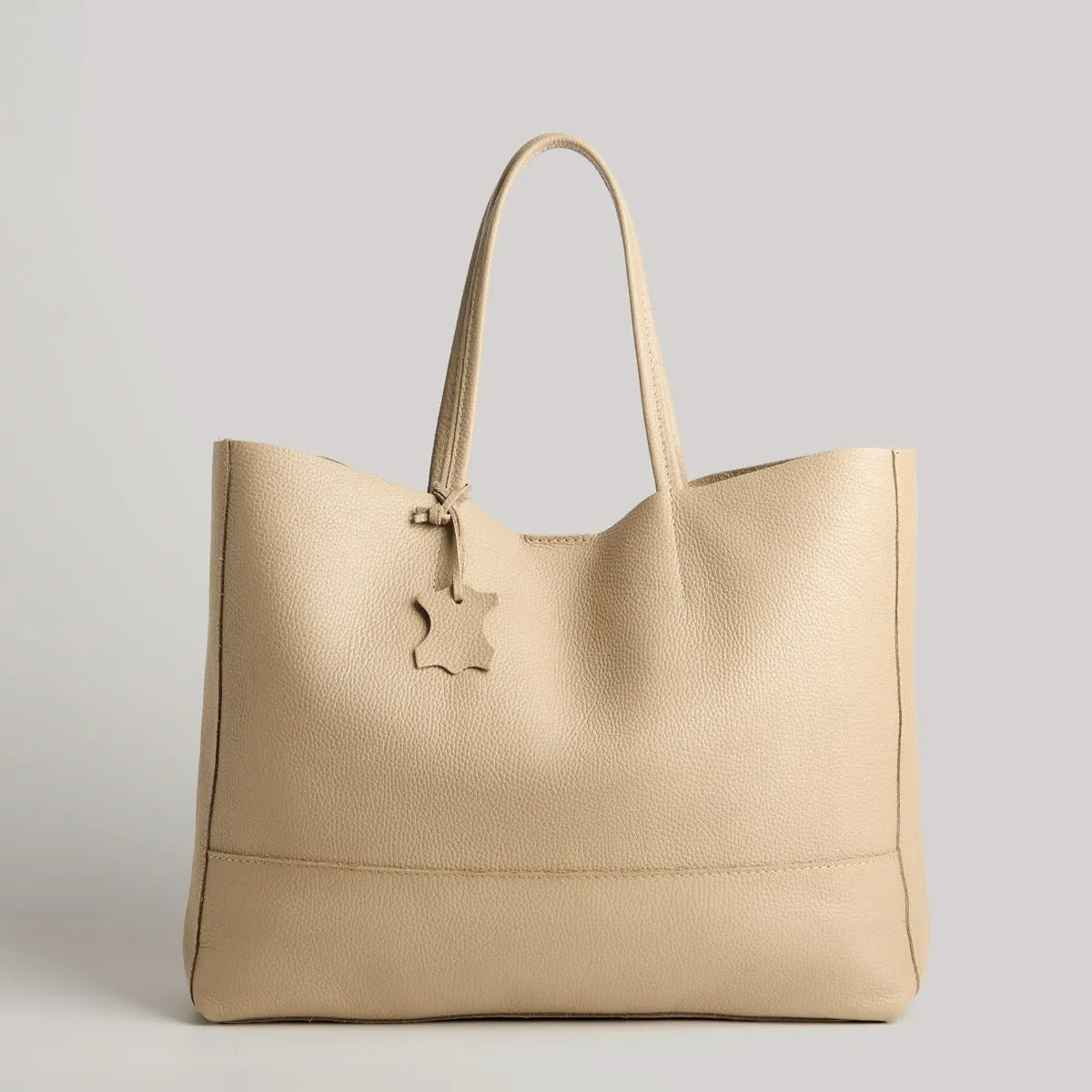 Die Umhängetasche "Susi" von flyliving aus dunkelgrauem Leder überzeugt mit zwei Henkeln und sternförmigem Anhänger - stilvoll präsentiert vor hellgrauem Hintergrund, die ideale Damenhandtasche für jeden Anlass.