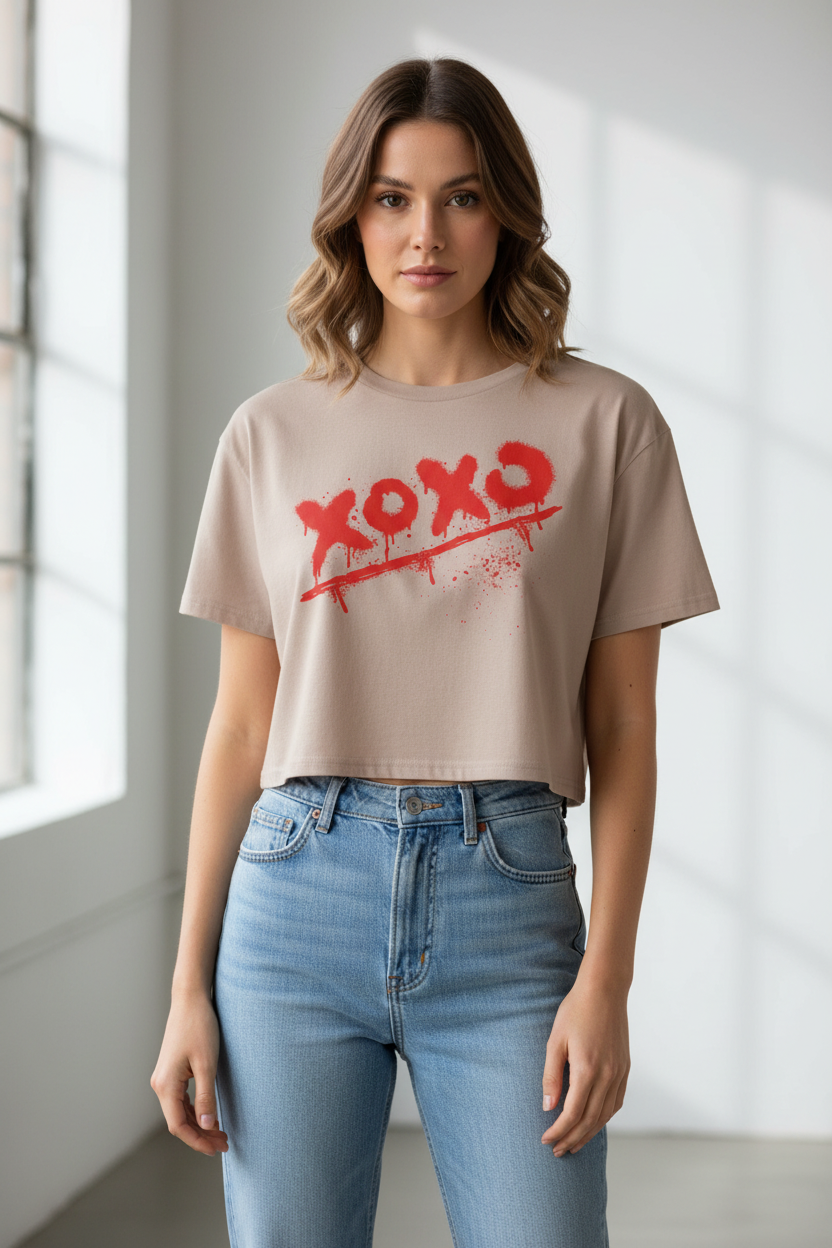 Beige cotton crop top by flyliving with a red graffiti 'xoxo' print, worn by a woman with light blue jeans.