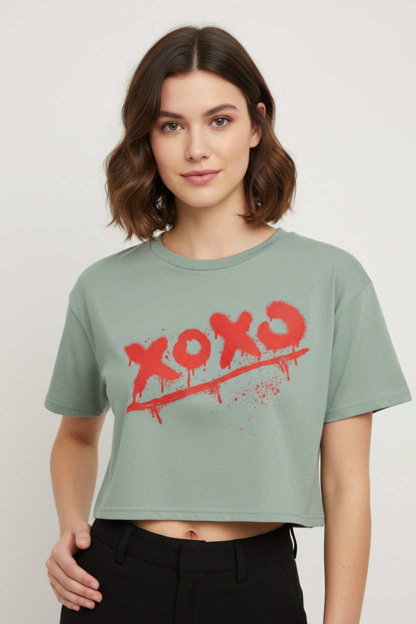 Sage green 100% combed cotton relaxed fit crop top by flyliving, featuring a red "xoxo" spray paint graphic and worn with black pants.