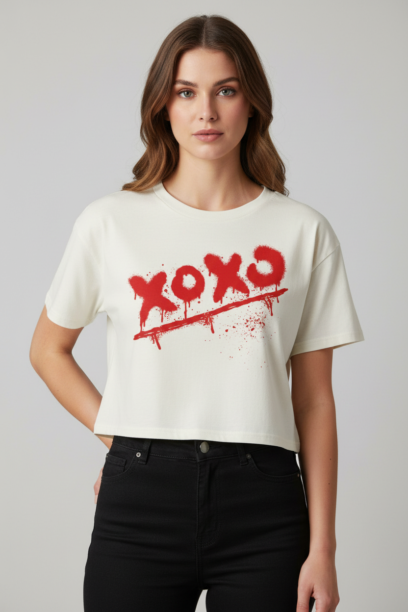 Relaxed fit cream combed cotton crop top with 'xoxo' graphic by flyliving, featuring red spray paint with drips, worn by a model in black jeans.