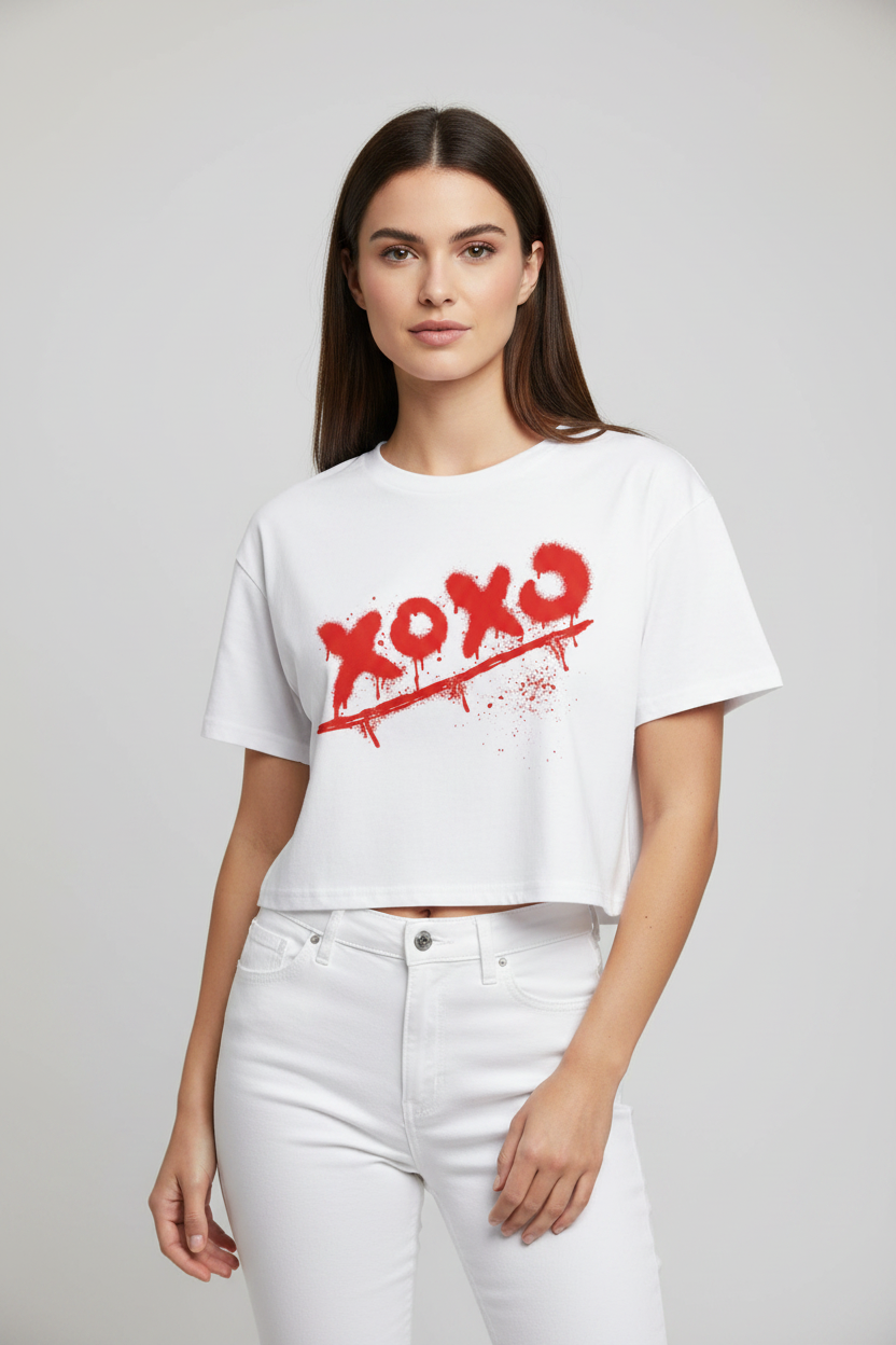 White relaxed fit crop top with a red "xoxo" graffiti-style print by flyliving, worn by a model in white jeans.