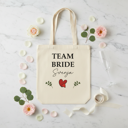 Creamfarbener JGA Jutebeutel aus Canvas mit team bride svenja in schwarz und roten Herzen sowie grünen Blättern