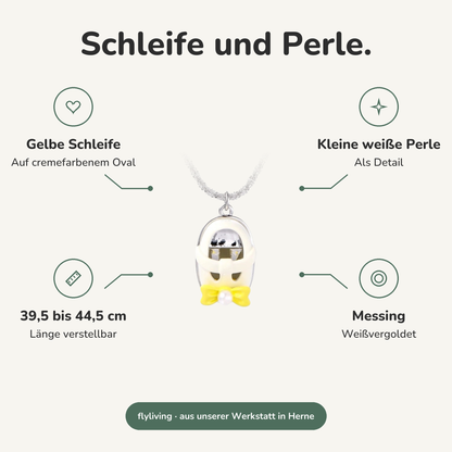 Erklärbild Schleife und Perle. Gelbe Schleife: Auf cremefarbenem Oval, Kleine weiße Perle: Als Detail, 39,5 bis 44,5 cm: Länge verstellbar, Messing: Weißvergoldet