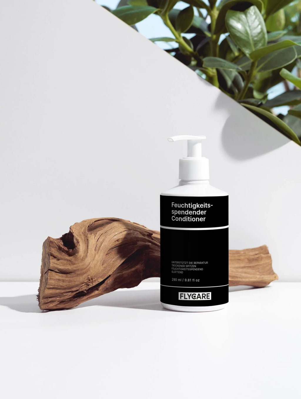 Feuchtigkeitsspendender Conditioner von Flycare, mit weißem Spender, vor einem Holzstück und grünen Blättern platziert.
