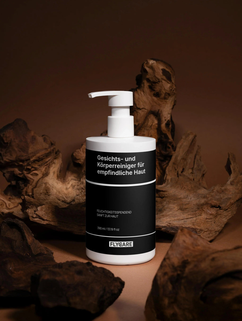 Reinigungsgel für Gesicht und Körper, für empfindliche Haut von Flycare, in weißer Flasche mit schwarzer Banderole, vor braunem Hintergrund mit Treibholz.
