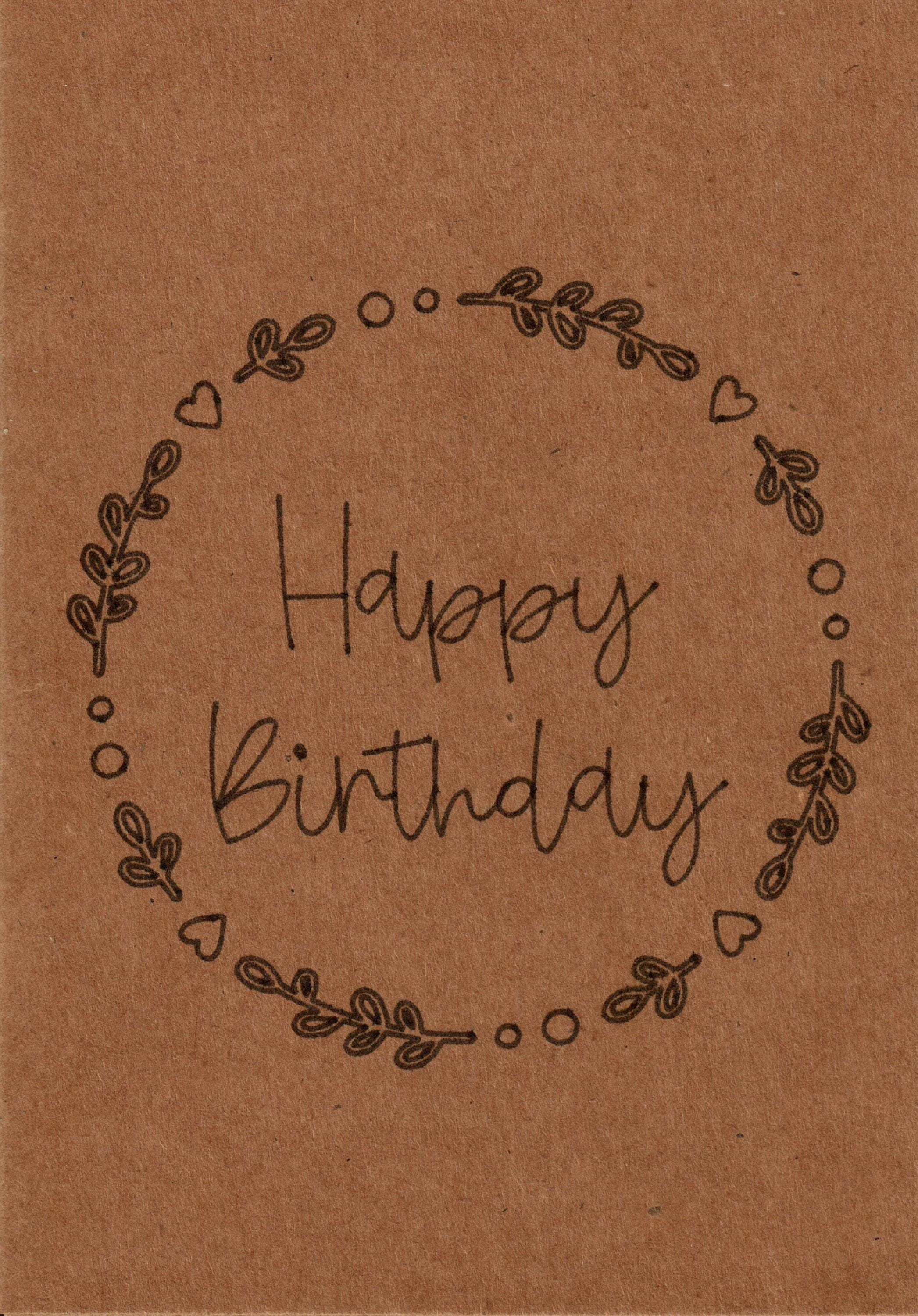 Geburtstagskarte aus braunem Kraftpapier mit schwarzem Schriftzug „Happy Birthday“, umrahmt von einem floralen Kreis aus Blättern und Herzen. Minimalistisches und elegantes Design für nachhaltige und stilvolle Geburtstagsgrüße.
