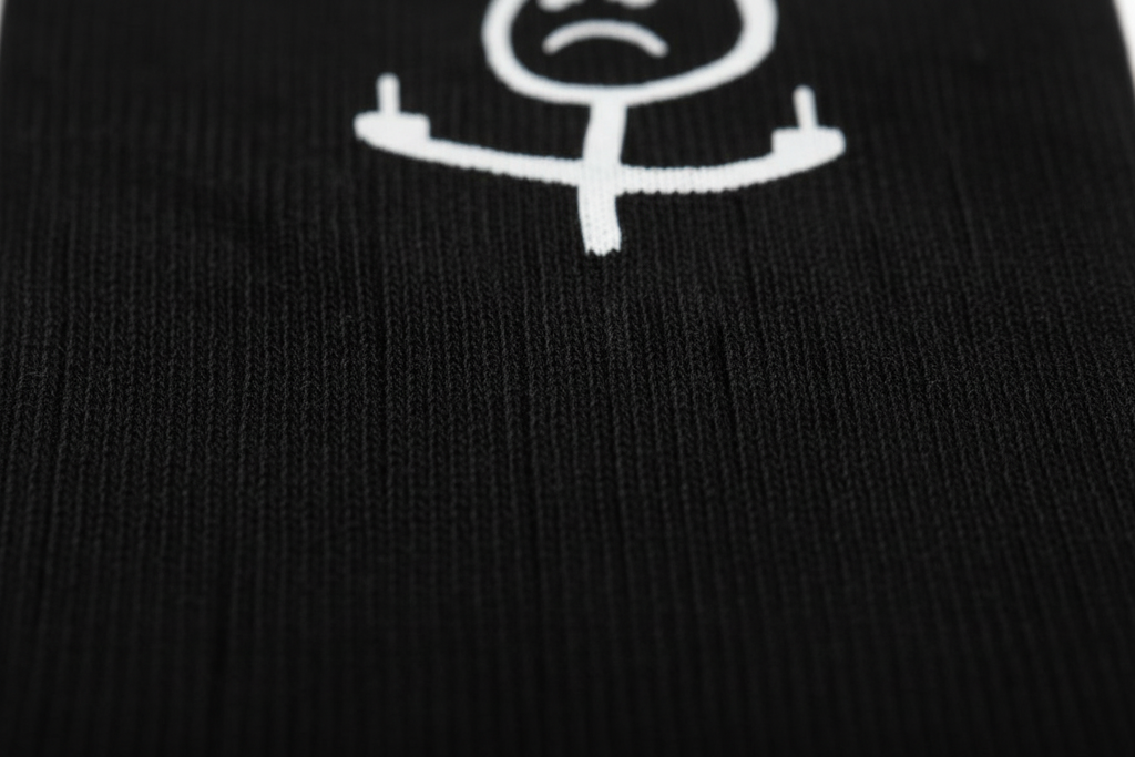 Unisex black cotton socks by flyliving, featuring a white sad stick figure giving two middle fingers, in a close-up view.