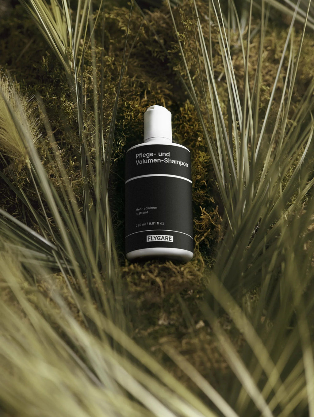 Pflege- und Volumen-Shampoo von Flycare, auf grünem Moos zwischen Gräsern liegend.