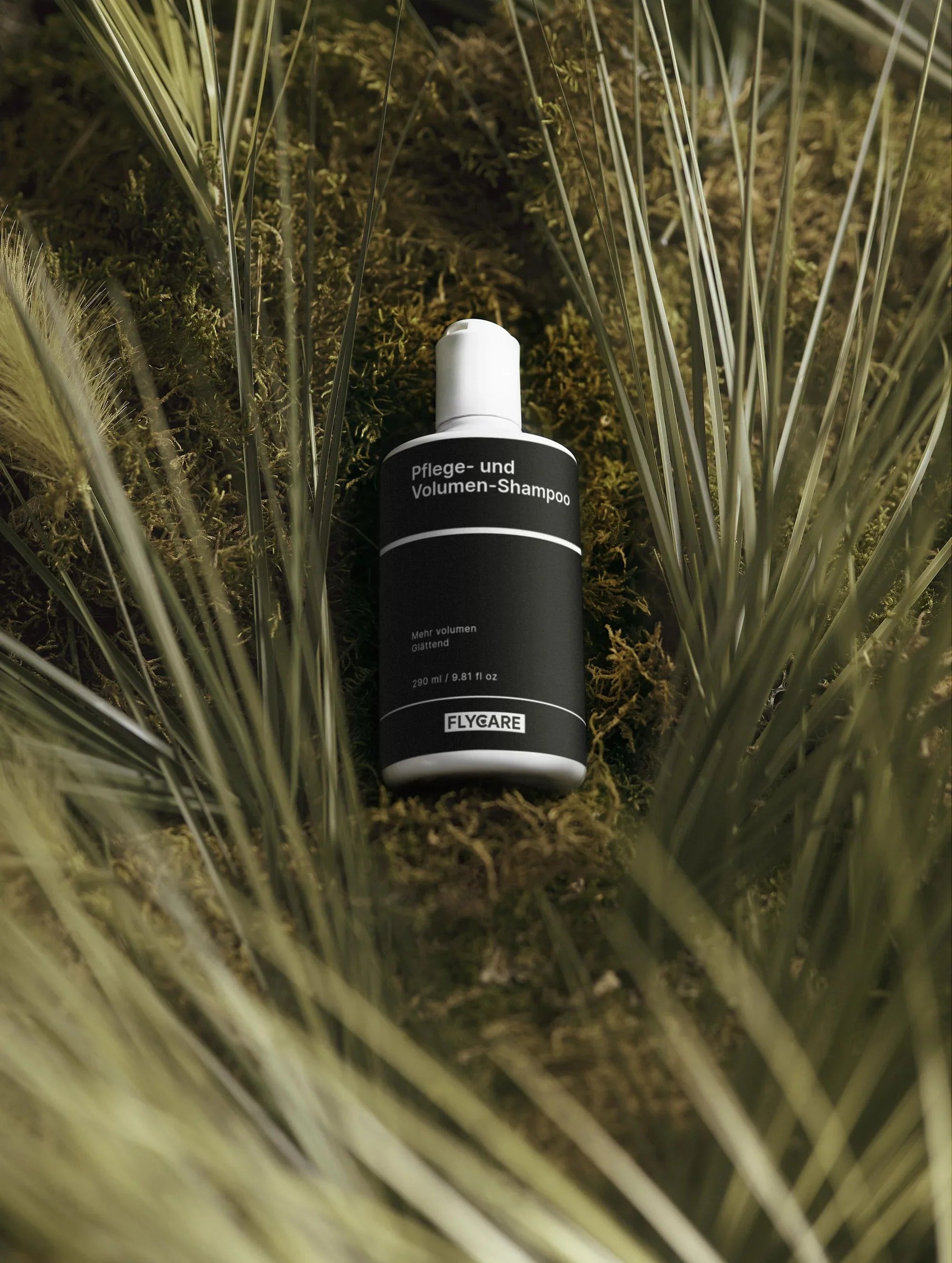 Pflege- und Volumen-Shampoo von Flycare, auf grünem Moos zwischen Gräsern liegend.