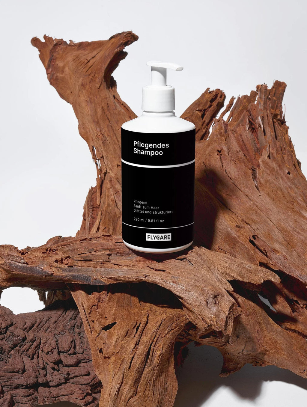 Pflegendes Shampoo von Flycare, präsentiert auf einem Stück strukturiertem Treibholz vor einem schlichten, weißen Hintergrund.