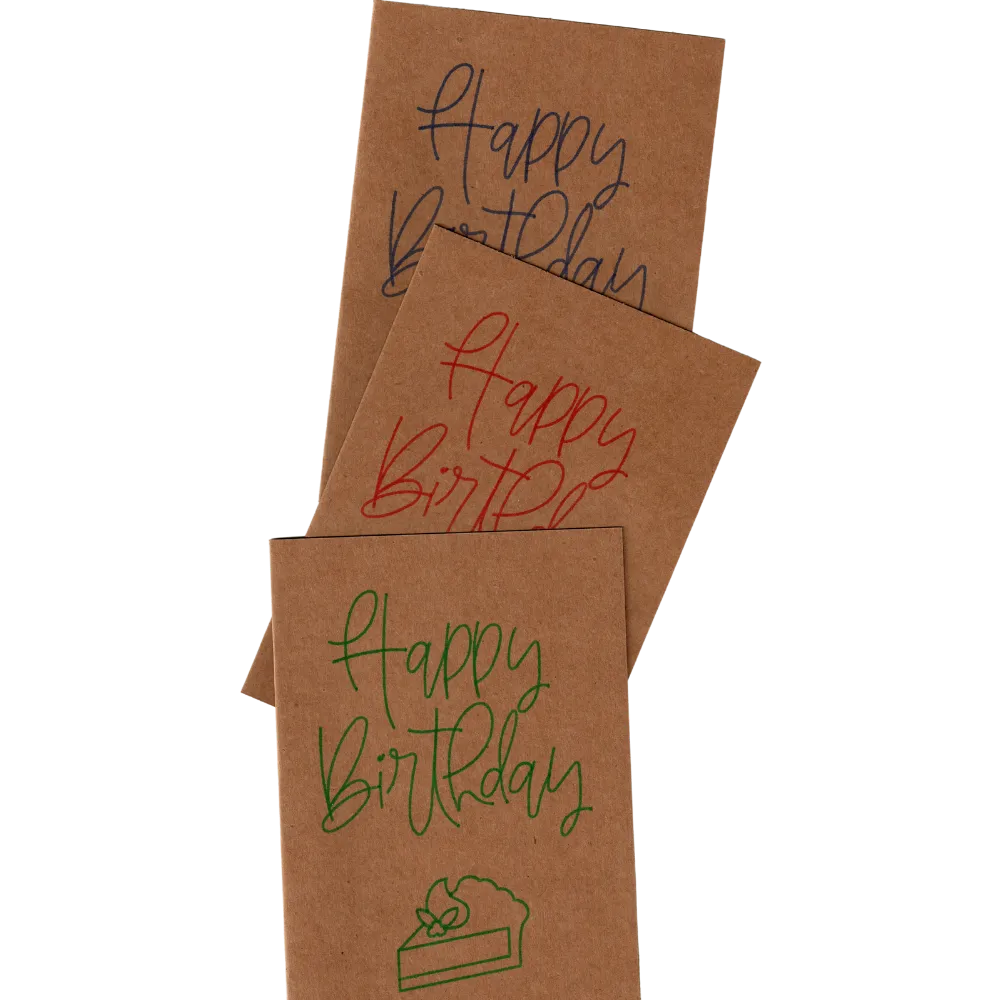Mehrere Karten aus Kraftpapier übereinander gelegt, mit dem Schriftzug "Happy Birthday" und einem gemalten Kuchenstück, in verschiedenen Farben.