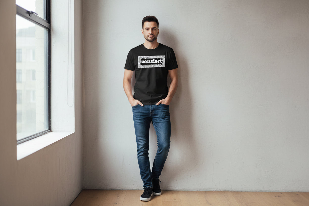 Black cotton T-shirt by flyliving, featuring a 'zensiert' design within a pixelated rectangle. Worn by a man in blue jeans.