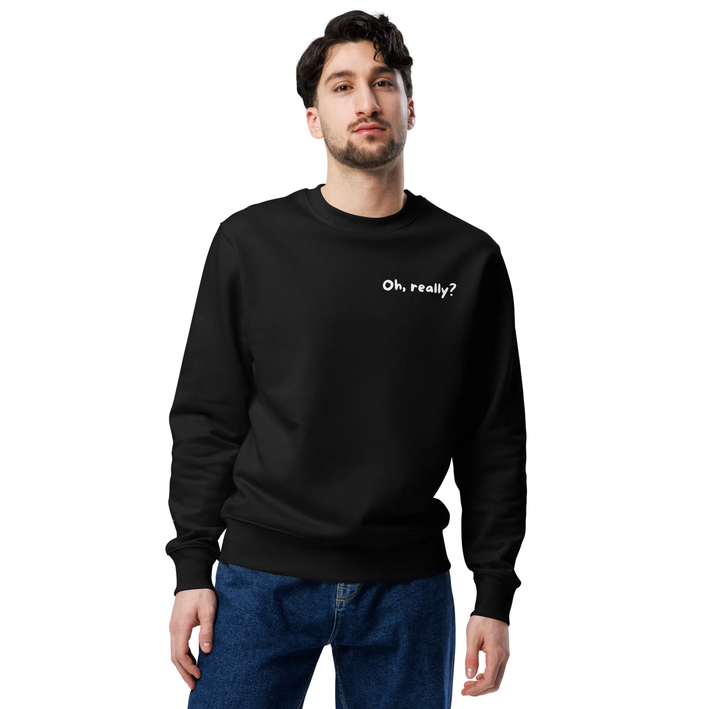 Ein Mann mit kurzen dunklen Haaren und Gesichtsbehaarung trägt den schwarzen flyliving Pullover "Oh, really?" aus organischer Baumwolle, mit kleiner weißer Brustschrift, steht vor einem schlichten schwarzen Hintergrund und schaut in die Kamera.